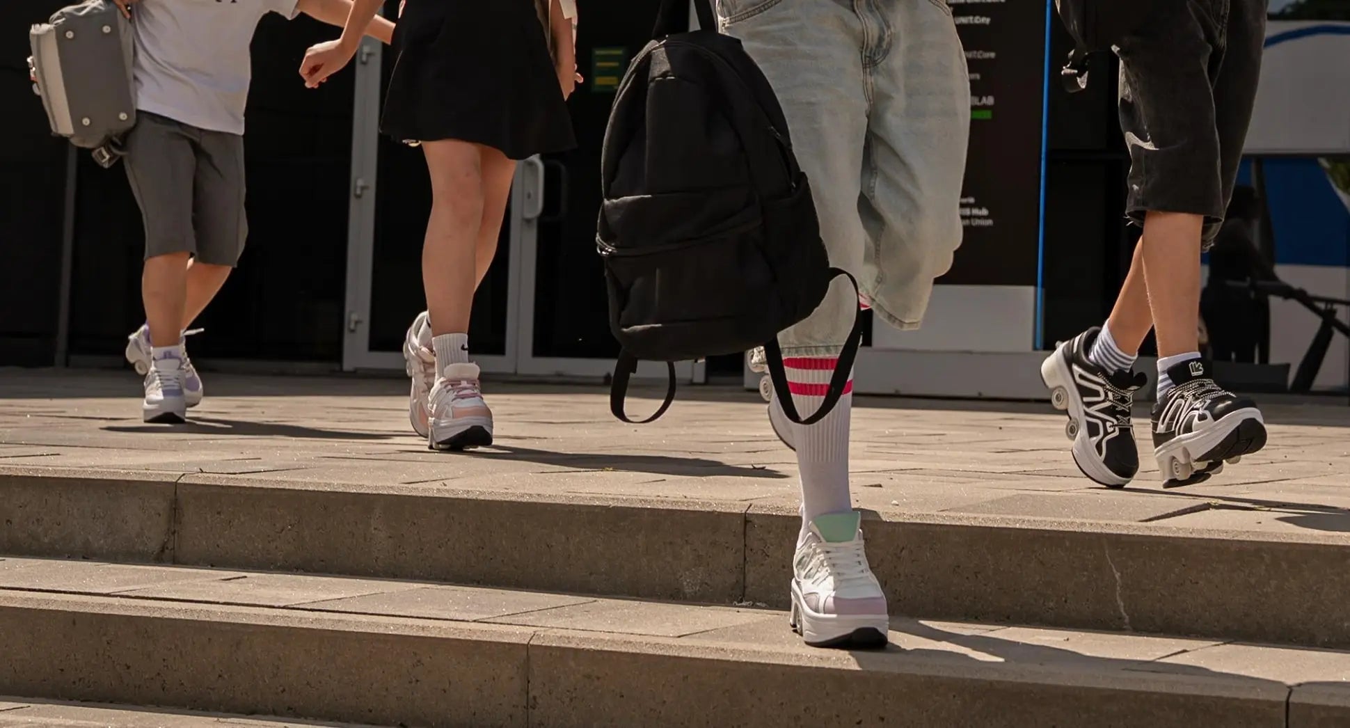 People walking up steps with a focus on their legs and roller shoes.